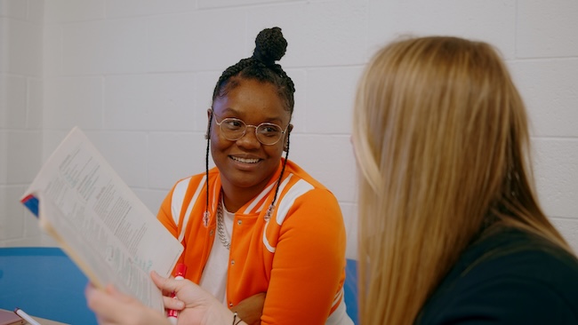 A student advisor and a student meet in a small conference room