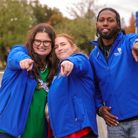 Three HFU alumni pose at a campus event all wearing the same 买球app jacket