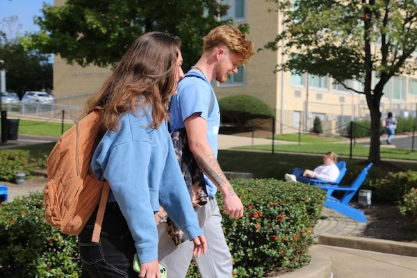 Two students in profile walking through a plaza on campus