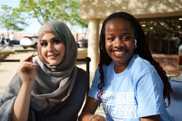 Two students sitting outside on campus smiling